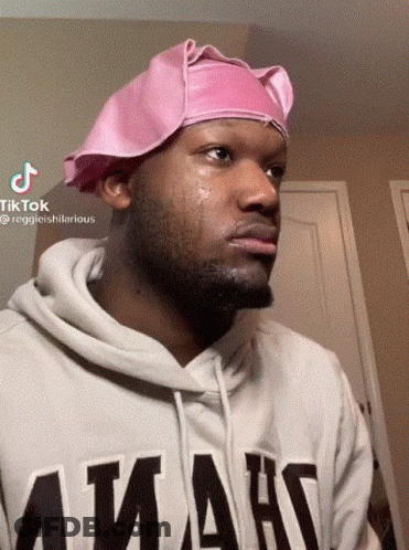 A Man Wearing A Pink Hat And A Hoodie That Says ' Amans ' GIF