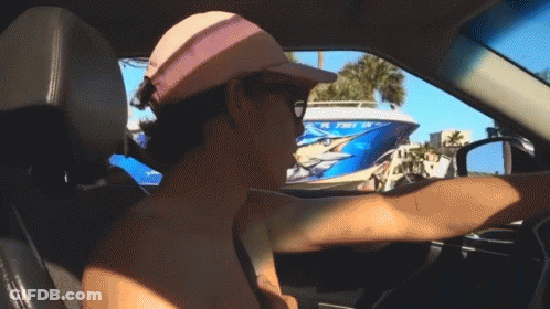 A Man Wearing A Pink Hat Is Driving A Car With A Boat In The Background That Says Florida On It GIF