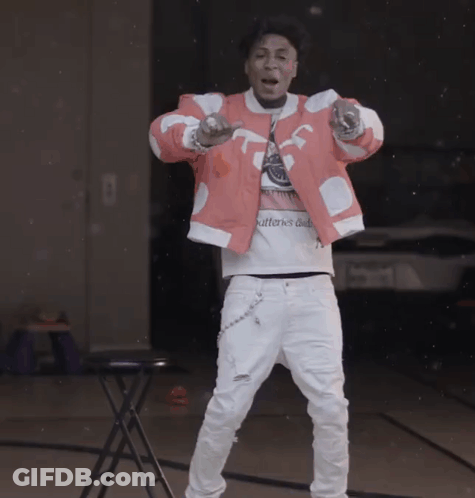 A Man Wearing A Pink Jacket And White Pants Is Standing In Front Of A Table With The Word Patterns On It GIF
