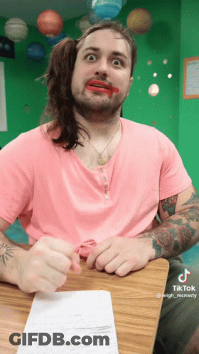 A Man Wearing A Pink Shirt Has Red Lipstick On His Lips GIF