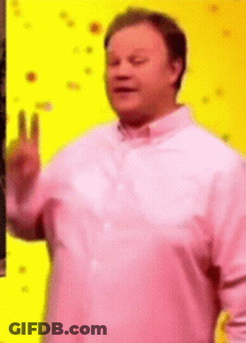 A Man Wearing A Pink Shirt Is Giving A Peace Sign . GIF