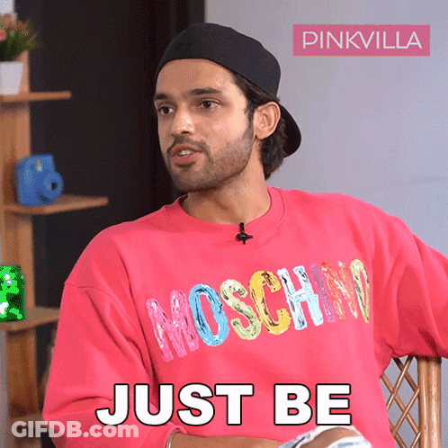 A Man Wearing A Pink Sweatshirt That Says Moschino On It GIF