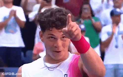 A Man Wearing A Pink Wristband Is Giving A Thumbs Up In Front Of A Crowd . GIF