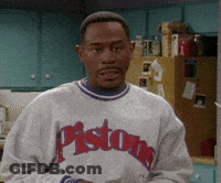 A Man Wearing A Pistons Sweatshirt Is Standing In Front Of A Refrigerator GIF