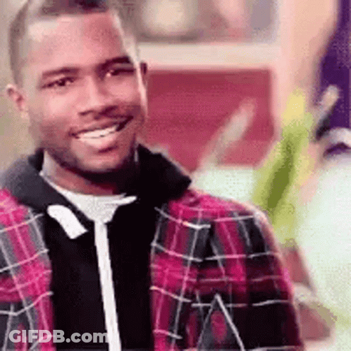A Man Wearing A Plaid Jacket And A Black Sweater Is Smiling . GIF