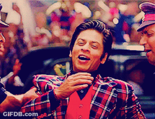 A Man Wearing A Plaid Jacket And A Red Vest Laughs GIF
