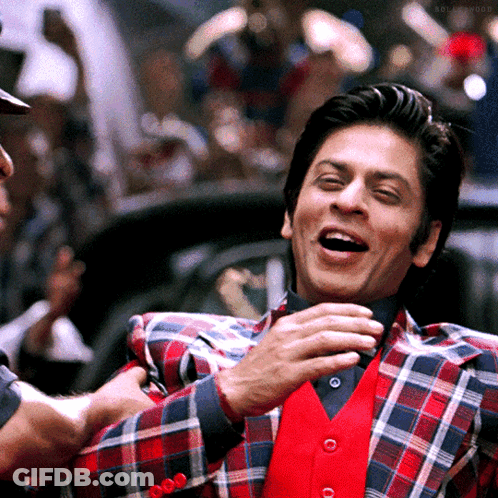 A Man Wearing A Plaid Jacket And A Red Vest Laughs GIF