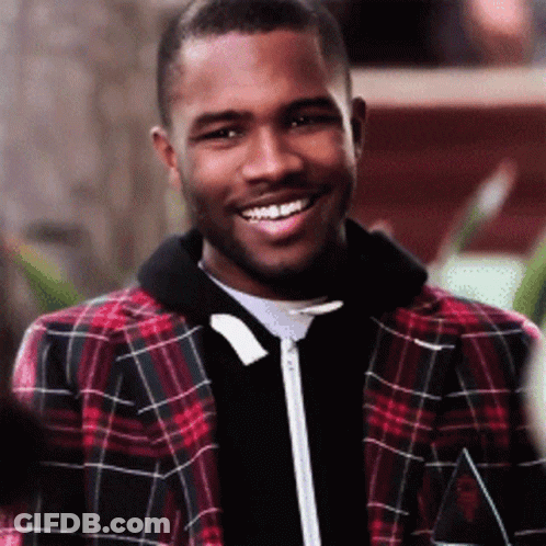 A Man Wearing A Plaid Jacket Is Smiling And Looking At The Camera GIF