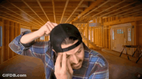 A Man Wearing A Plaid Shirt And A Black Hat Is In A Room Under Construction GIF