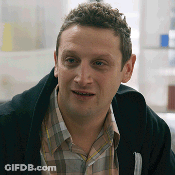 A Man Wearing A Plaid Shirt And A Black Jacket Smiles GIF