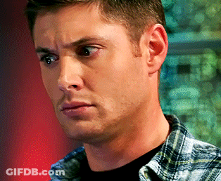 A Man Wearing A Plaid Shirt And A Black Shirt Looks At The Camera GIF