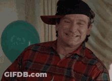 A Man Wearing A Plaid Shirt And A Hat Is Smiling And Saying Wazzup . GIF