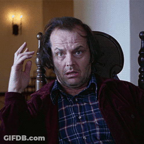 A Man Wearing A Plaid Shirt And A Red Jacket Is Sitting In A Chair GIF