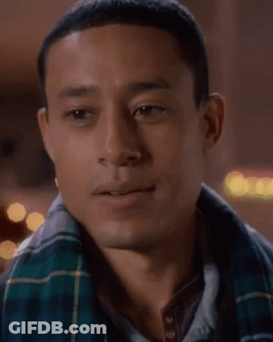 A Man Wearing A Plaid Shirt And A Scarf Is Smiling GIF
