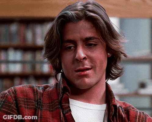 A Man Wearing A Plaid Shirt And A White Shirt Looks At The Camera GIF