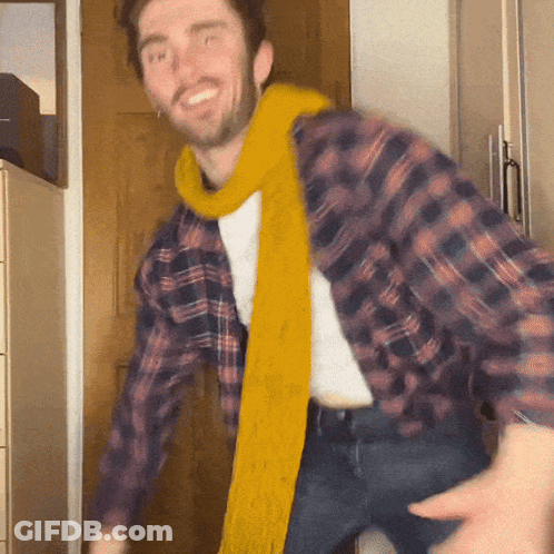 A Man Wearing A Plaid Shirt And A Yellow Scarf Dancing GIF