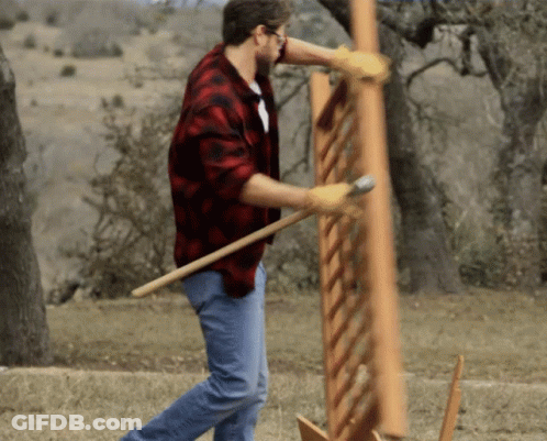 A Man Wearing A Plaid Shirt And Gloves Is Holding A Large Piece Of Wood GIF