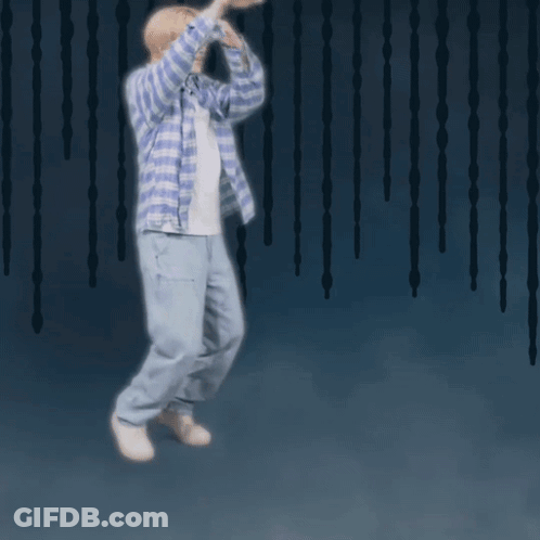 A Man Wearing A Plaid Shirt And Jeans Is Jumping In The Air GIF