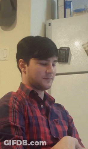 Man In Plaid Shirt Sitting By Fridge GIF