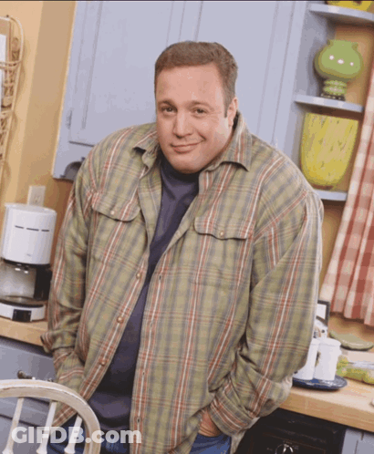 A Man Wearing A Plaid Shirt Is Standing In A Kitchen GIF