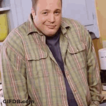 A Man Wearing A Plaid Shirt Is Standing In A Kitchen . GIF