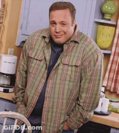 A Man Wearing A Plaid Shirt Is Standing In A Kitchen With His Hands In His Pockets GIF