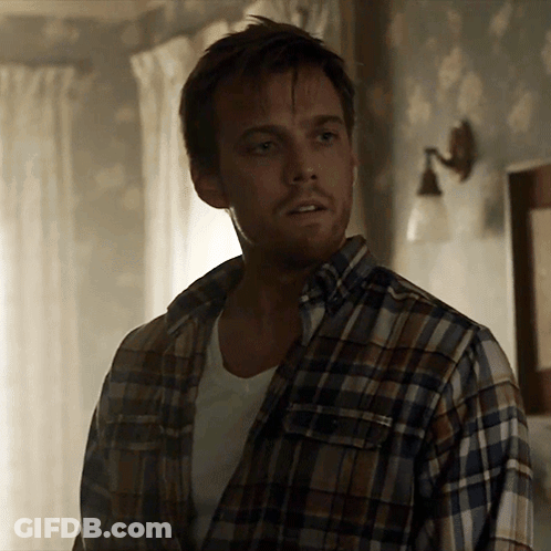 A Man Wearing A Plaid Shirt Is Standing In A Room GIF