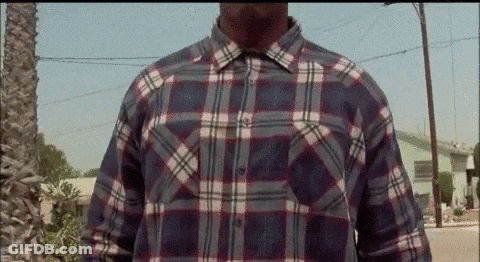 A Man Wearing A Plaid Shirt Is Standing In Front Of A Street . GIF