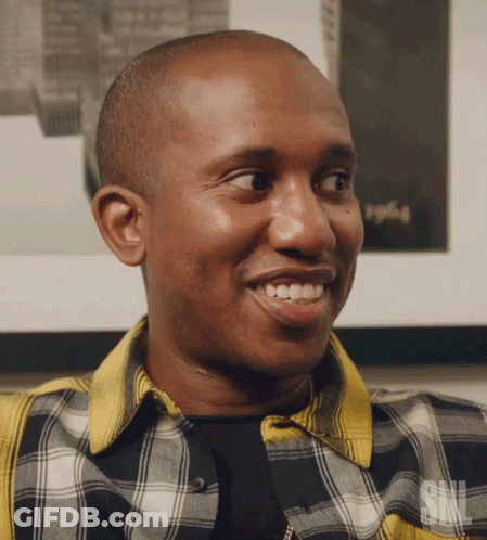 A Man Wearing A Plaid Shirt With The Letters Snl On The Bottom GIF