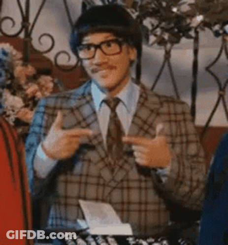 A Man Wearing A Plaid Suit And Tie Is Pointing At Something . GIF