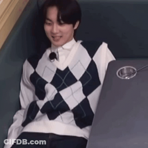 A Man Wearing A Plaid Vest Is Sitting At A Table With A Spoon In It . GIF