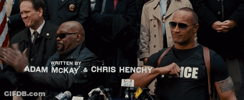A Man Wearing A Police Shirt Is Standing In Front Of A Crowd Of People GIF