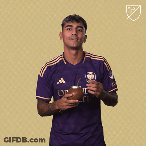 A Man Wearing A Purple Adidas Shirt Is Holding A Soccer Ball GIF