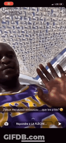 A Man Wearing A Purple And Yellow Lakers Jersey Is Waving His Hand GIF