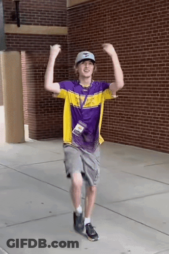 A Man Wearing A Purple And Yellow Shirt Is Dancing On The Sidewalk . GIF