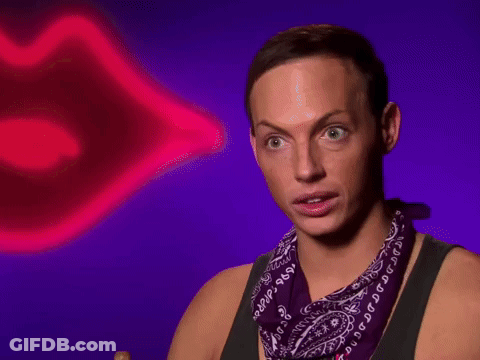 A Man Wearing A Purple Bandana Is Sitting In Front Of A Neon Lip GIF