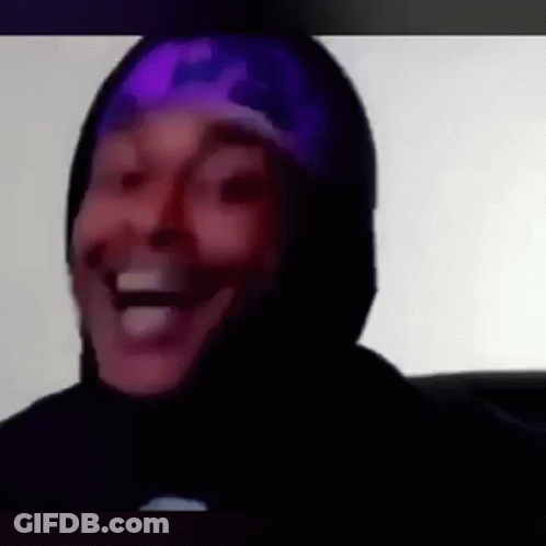 A Man Wearing A Purple Hat And A Black Hoodie Is Laughing . GIF
