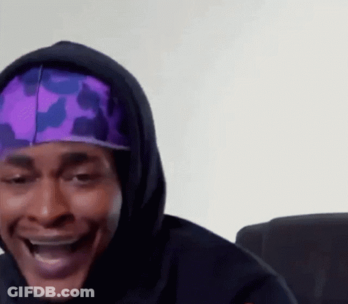 A Man Wearing A Purple Hat And A Black Hoodie Is Smiling . GIF