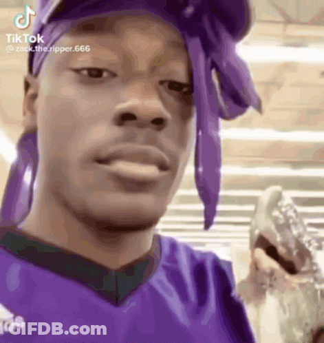 A Man Wearing A Purple Headband And A Purple Shirt Is Holding A Glass Of Water . GIF