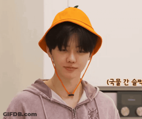 A Man Wearing A Purple Hoodie And An Orange Hat With A Green Leaf On It GIF