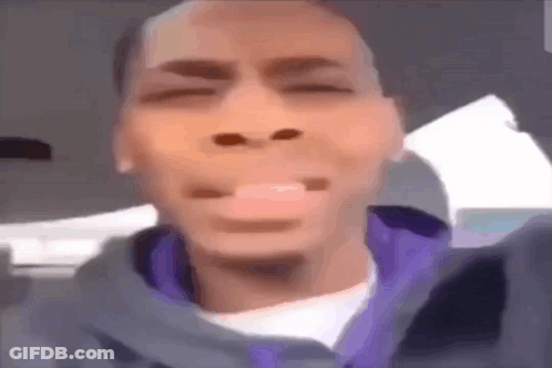 A Man Wearing A Purple Jacket Is Making A Funny Face . GIF
