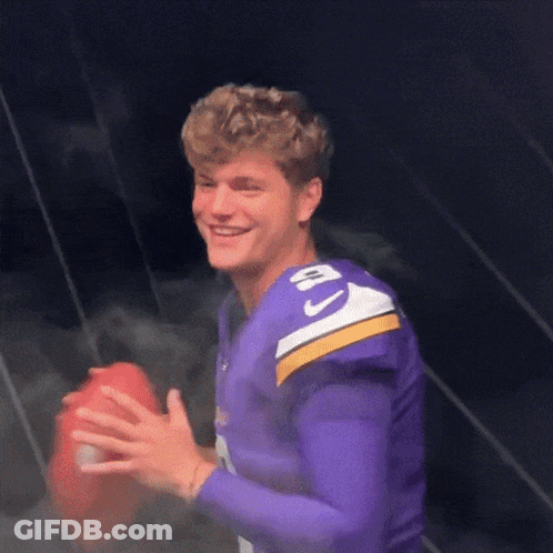 A Man Wearing A Purple Jersey With The Number 10 On It Holds A Football GIF