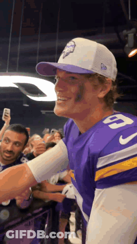 A Man Wearing A Purple Jersey With The Number 9 On It Shakes Hands With A Fan GIF
