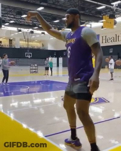 A Man Wearing A Purple Lakers Jersey Is Dancing On A Basketball Court GIF
