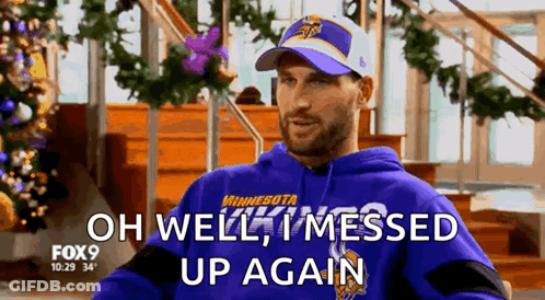A Man Wearing A Purple Minnesota Vikings Sweatshirt Is Sitting In Front Of A Christmas Tree . GIF