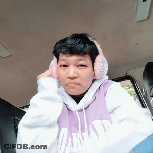 A Man Wearing A Purple Oakland Sweatshirt And Ear Muffs GIF