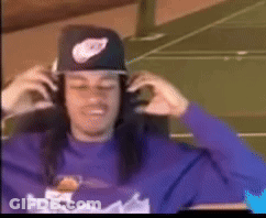 A Man Wearing A Purple Shirt And A Nike Hat Is Adjusting His Headphones . GIF