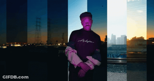 A Man Wearing A Purple Shirt That Says Anderson Stands In Front Of A City Skyline GIF