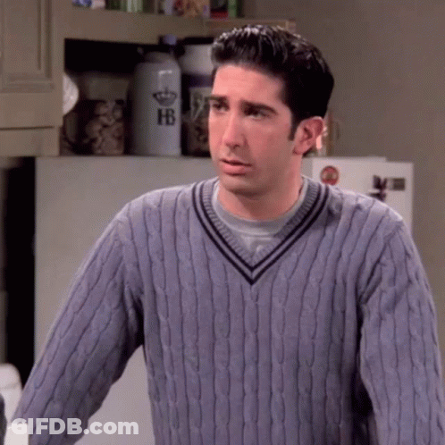 A Man Wearing A Purple Sweater Is Standing In A Kitchen . GIF