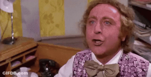 A Man Wearing A Purple Vest And Bow Tie Is Sitting At A Desk . GIF